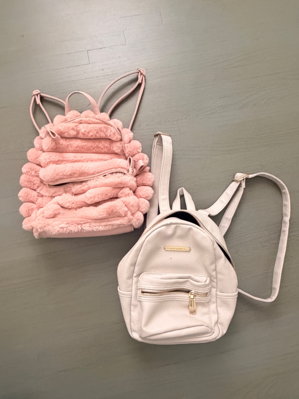 Two cute mini backpacks, one pink fuzzy, one white